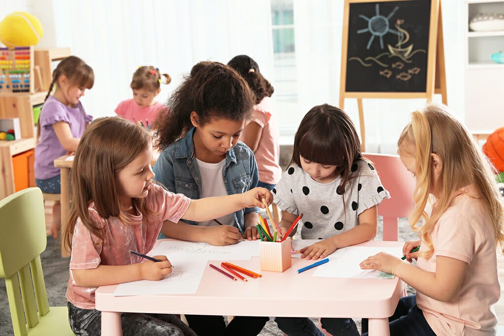 Adorable children drawing together at table indoors. Kindergarte
